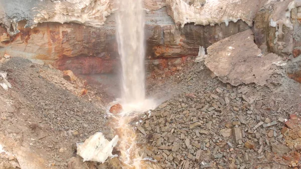 Blick auf den Wasserfall vor dem Hintergrund schmutzigen Mineralgesteins. Aktien. Schmutziger Wasserfall rieselt mit Erdrutschresten mineralogische braune Felswand hinunter — Stockfoto