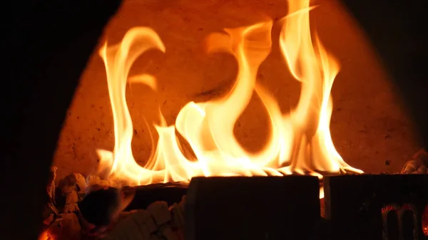 Primer plano de la llama de fuego ardiendo en el horno. Una trampa. Llama de fuego bellamente ardiente en la estufa de leña tradicional. Fuego en la estufa para cocinar —  Fotos de Stock