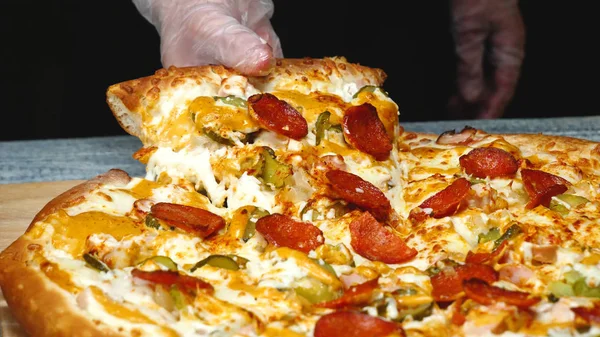 Крупный план человека берет вкусный кусок пиццы с сыром. Рамка. Мужчина берет кусок итальянской пиццы и тянет аппетитный расплавленный сыр — стоковое фото