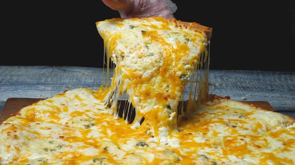 Крупный план человека берет вкусный кусок пиццы с сыром. Рамка. Мужчина берет кусок итальянской пиццы и тянет аппетитный расплавленный сыр — стоковое фото