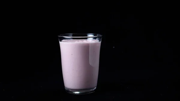 Erdbeer-Milchshake isoliert auf schwarzem Hintergrund. Rahmen. transparentes Glas gefüllt mit rosa Milchshake steht auf schwarzem Hintergrund ohne Bewegung — Stockfoto