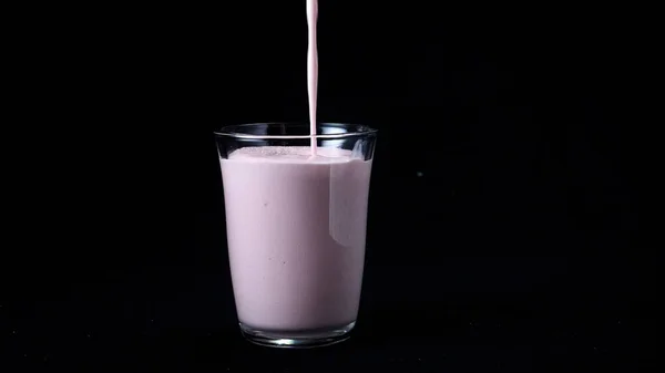 Aardbei melk schudden geïsoleerd op zwarte achtergrond. In transparant glas giet viskeuze roze milkshake op zwarte achtergrond. Coole milkshakes — Stockfoto