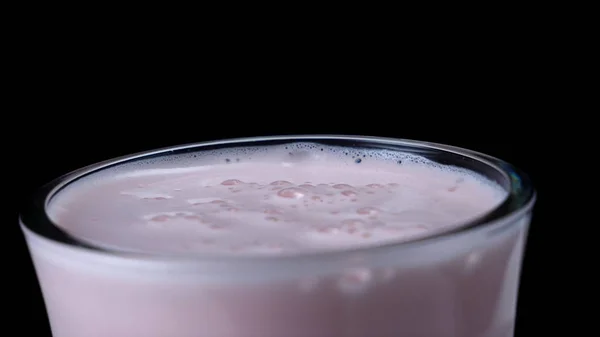 Primer plano del batido de fresa sobre fondo negro aislado. Una trampa. Cóctel rosa lechoso con espuma gruesa y burbujas sobre fondo negro — Foto de Stock