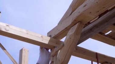 İşçiler tahtaları inşa edip yığlar. Klip. İşçiler evin şantiyegüzel ahşap kirişler yükleyin. Gökyüzünün arka planda inşaat modunda ahşap ev