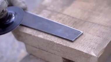 İşçi parlatma demir tahtası yakın çekim. Klip. Eldivenli adam çelik düz detay disk aracını parlatır. Doğrama işlemi parlatma aleti parça demir
