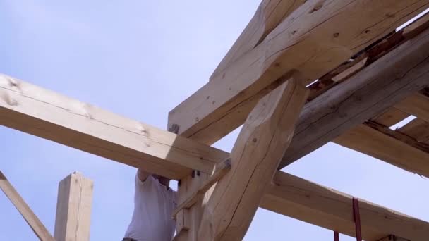 Werknemers bouwen en stapelen planken houten huis. Clip. Werknemers installeren prachtige houten balken op bouwplaats van huis. Houten huis in de modus van de bouw op de achtergrond van de hemel — Stockvideo