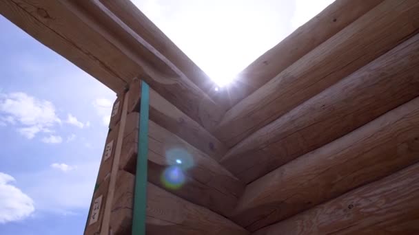 Vista ravvicinata della struttura in legno della casa. Clip. Casa di costruzione di buoni tronchi di legno. Costruzione di casa in legno su cielo blu — Video Stock