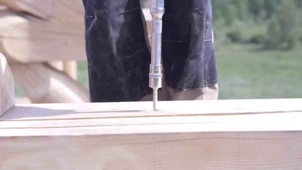 Primer plano de los taladros del trabajador tablero de madera. Clip. Taladros de carpintero tronco con taladro especial para la construcción de casa de madera — Vídeo de stock