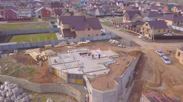 Widok z góry betonowej podstawy domu. Klip. Pracownicy na budowie sprawdzić betonowa podstawa domu w budowie na tle domków wiejskich — Wideo stockowe