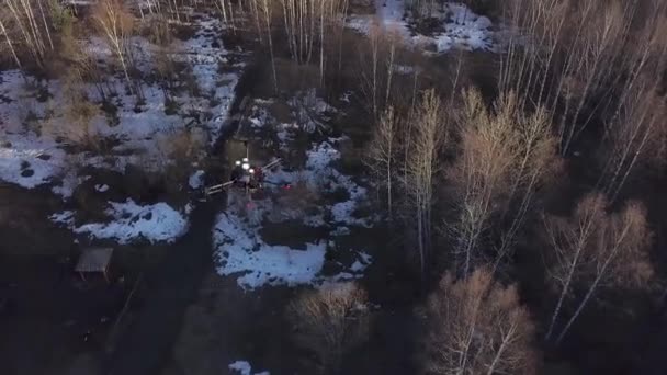 Blick von oben auf Quadrocopter, der über Wald fliegt. Clip. neuer leistungsstarker Quadrocopter macht Bilder aus der Luft über kahlen Wald mit Schnee — Stockvideo