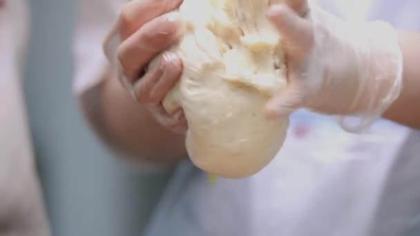 Closeup of chef kneaded yeast dough. Stock footage. Cook at industrial enterprise in form and gloves prepares easter cakes. Professional baker prepares dough with raisins for cakes — Stock Video