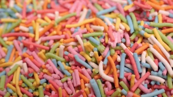 Close-up background of colorful food sprinkles. Stock footage. Beautiful long sprinkles in rainbow color in large quantities. Bright multi-colored sprinkles to decorate sweet pastries — Stock Video