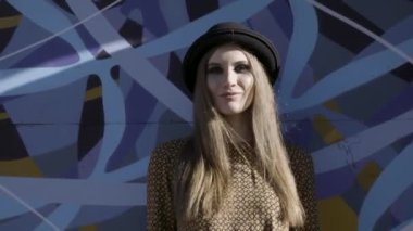 Şehir caddesinde mavi graffity arka plan üzerinde siyah şapka ve bataklık renkli gömlek giyen bir kız. Eylem. Bir şapka güzel kadın ve dumanlı gözleri makyaj ile, şehir tarzı kavramı.