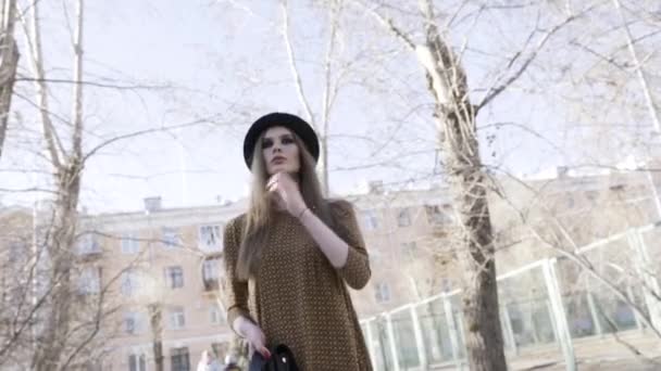 Buttom view of the stylish pretty woman touching her hair and walking outdoor in black leather jacket and a hat in autumn. Action. Model girl wearing a brown blouze, street fashion. — Stock Video