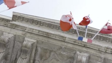 Parlak gökyüzü arka plan, Fransa rüzgarda sallanan bayraklar ile eski bir binaya aşağıdan görünümü. Eylem. Elçilikte rüzgarda dalgadalga birkaç bayrak.