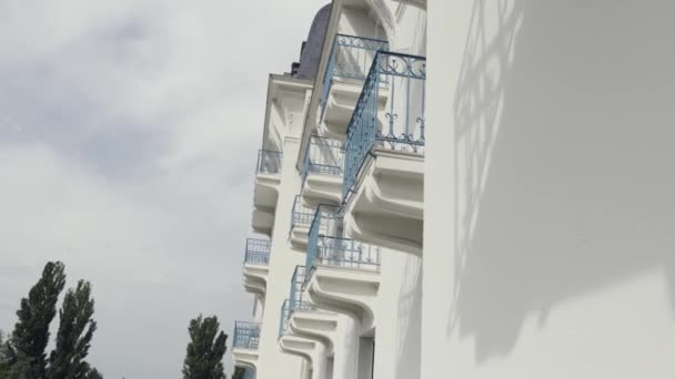 Vista laterale di balconi con ringhiera in ferro battuto blu di edificio moderno, sfondo architettonico. Azione. Parete bianca di una casa con balconi contro cielo nuvoloso . — Video Stock