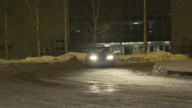 Gece şehir caddesinde karlı bir yolda sürüklenen binek otomobil, tehlikeli bir yarış. Eylem. Karanlıkta dönerken bir arabanın kızağa dönüşmesi.