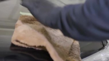 Siyah eldivenli adam eli için kapatın araba yıkamada araba camını yıkamak, temizlik hizmeti. Eylem. Araba bakım hizmeti çalışanı bir araba temizliği için mikrofiber bez kullanarak.
