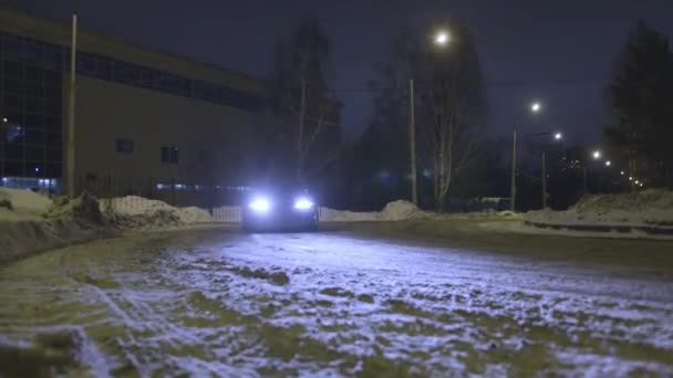 Пассажирский автомобиль дрейфует по снежной дороге на городской улице ночью, опасная гонка. Начали. Автомобиль врезается в занос во время поворота в темноте . — стоковое видео
