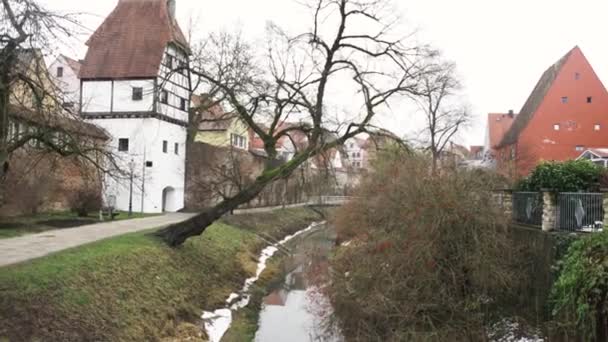 Paysage printanier des maisons de ville fluviales, vue canal. L'art. Petites maisons le long de la rivière avec de l'herbe et des arbres sur les pentes de la rivière . — Video