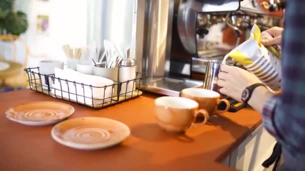 Vista laterale di un barista professionista che mette il latte fresco nella brocca della caffetteria, preparazione di bevande calde. Art. Macchina da caffè, tazze e piatti, e altre cose alla caffetteria . — Video Stock