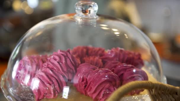 Gros plan sur les meringues roses sous la cloche de verre de la pâtisserie au café français, concept alimentaire. L'art. Beaux gâteaux roses couchés sur un plateau sur fond flou . — Video