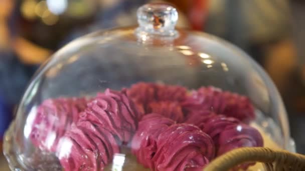 Gros plan sur les meringues roses sous la loche en verre de la pâtisserie au café français, concept culinaire. L'art. Beaux gâteaux roses couchés sur un plateau sur fond flou . — Video