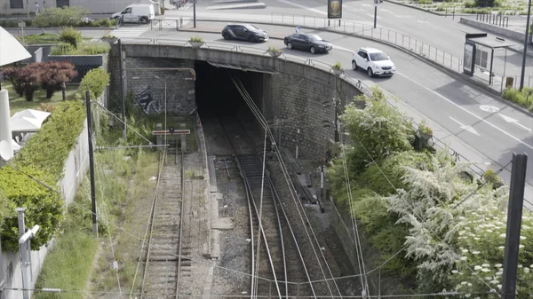 O túnel em Estocolmo com uma rua acima com tráfego leve, pessoas ambulantes e casas de vários andares brancas. Acção. O contraste de grama verde e estrada da cidade branca com edifícios . — Fotografia de Stock