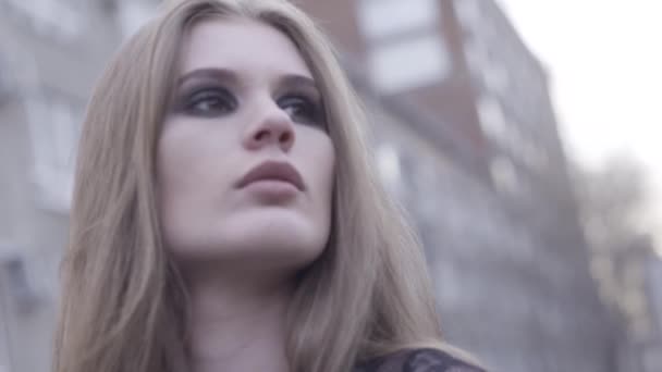 Retrato de belleza al aire libre de una joven morena mirando a un lado sobre un fondo borroso de la línea de la ciudad. Acción. Primer plano para la cara de la mujer con ojos ahumados brillantes, maquillaje concepto . — Vídeos de Stock