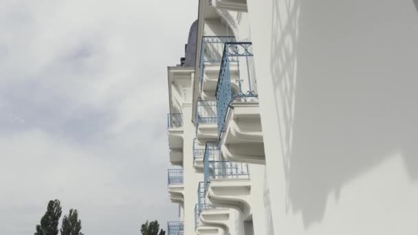 Vue latérale des balcons avec balustrade en fer forgé bleu du bâtiment moderne, arrière-plan architectural. L'action. Mur blanc d'une maison avec balcons contre ciel nuageux . — Video