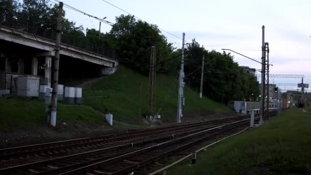 Az üres vasúti pályák megtekintése a külvárosokban. Stock Footage. Elágazó vasút zöld füvön a bokrok hátterére és a távolságból elhaladó emberekre — Stock videók