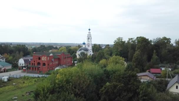 Top uitzicht op de witte kerk op de achtergrond van de stad in de zomer. Stock footage. Panoramisch uitzicht op de buitenwijken met groene gebieden, waaronder de witte kerk. Religie en zijn plaats in het leven — Stockvideo