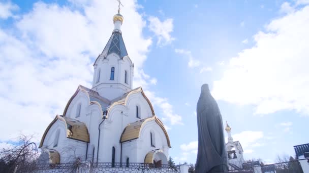 Estátua de metal de padre no fundo da igreja. Imagens de stock. Bela estátua de ministro sagrado com detalhes claros em frente à igreja contra o céu azul. Conceito de religião — Vídeo de Stock