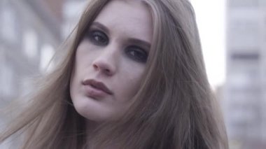 Şehir sokaklarının arka planında kahverengi gözlü güzel kahverengi saçlı kadının yüzüne yakın çekim yapın. Başla. Parlak dumanlı gözlü bir kızın şehvetli yüzü.