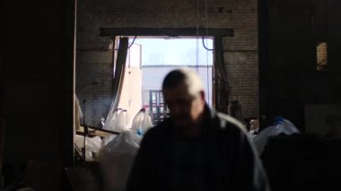 İşçiler bitkinin eski deposunda çalışır. Stok görüntüleri. Fabrika işçileri açık kapılar arka planda eski depo dağınık odasında temizlenir