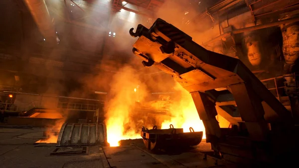 Un mecanismo con ganchos en la tienda caliente con humo creciente y fuego ardiente en la planta metalúrgica. Imágenes de archivo. Industria pesada, equipos en la fábrica de acero . —  Fotos de Stock