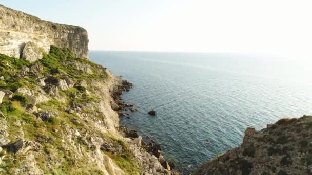 Spectaculair uitzicht op steile dliffs in de Oceaan, Ierland. Shot. Groene helling in de buurt van kalm water en de eindeloze horizon op heldere blauwe hemel achtergrond. — Stockvideo