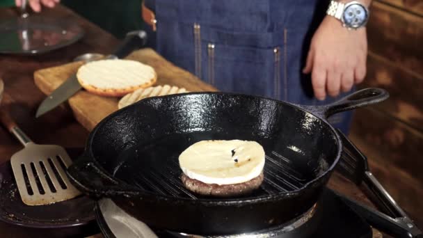 Una hamburguesa frita en una parrilla de hierro fundido. Imágenes de archivo. Hamburguesa Patty se prepara en la parrilla — Vídeos de Stock