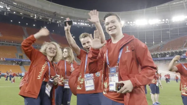 Russland, Moskva - 15. juli 2018: Fotballtilhengere i røde klær som går på grønn bane på stadion, sportskonsept. Handling. Fotballsupportere som morer seg og kommuniserer . – stockfoto