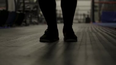 İp atlayan kaslı adamın bacakları için yakın çekim, karanlık spor salonunda egzersiz, spor ve sağlıklı yaşam tarzı konsepti. Başla. Erkek boksör ip atlarken tökezliyor.