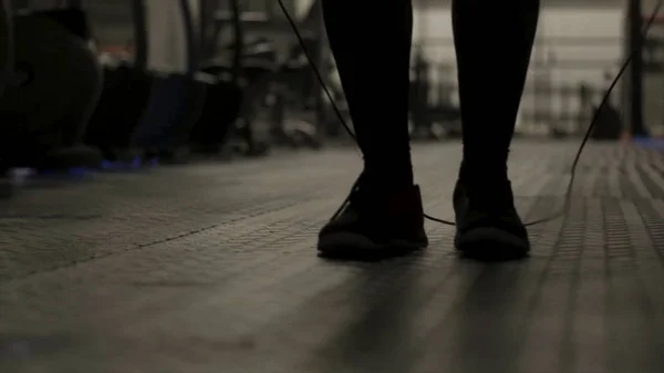 Крупним планом для ніг м'язистого чоловіка, який пропускає мотузку, займається в темному спортзалі, спортом і концепцією здорового способу життя. Дія. Чоловік боксер спотикається під час стрибків мотузки . — стокове фото