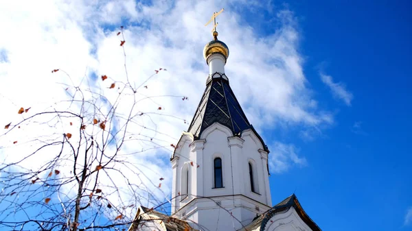 Bílý kostel proti modré obloze se zlatými dómy. Skladní záběry. Pohled na zlatou kopuli chrámu proti modrému nebi — Stock fotografie