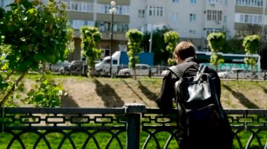 Yaz aylarında nehir tarafından şehirdeki genç adamın arka görünümü. Stok görüntüleri. Yaz aylarında şehir manzarası
