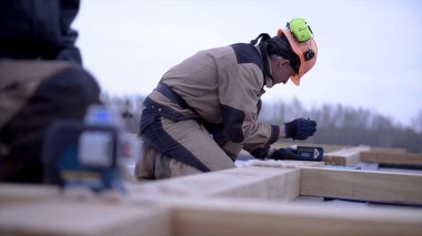 İşçi ahşap tahta ölçümleri notlar alır. Klip. Kask şeklinde işçi inşaat testere için ahşap tahta üzerinde ölçümler imar kayıtları