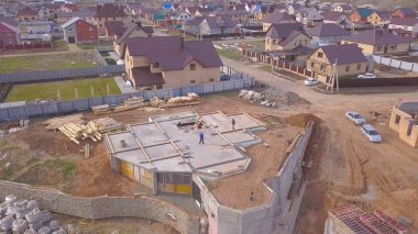Evin beton tabanıüst görünümü. Klip. Şantiyede çalışanlar, kırsal evlerin arka planında inşaat aşamasındaki evin beton temelini kontrol ediyor