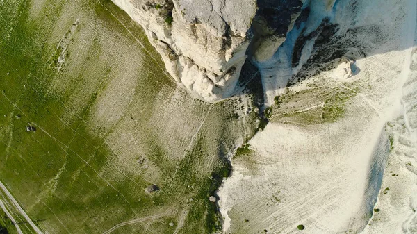 Κορυφαία θέα του όμορφου λευκού βράχου με πράσινο γρασίδι στο φόντο του γαλάζιου ουρανού. Πυροβολισμό. Πανόραμα λευκού βράχου με πράσινο χωράφι με τα πόδια του καλοκαιριού — Φωτογραφία Αρχείου