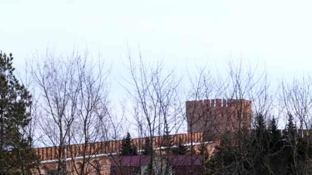 Fortaleza de ladrillo con torre redonda en el fondo del cielo. Imágenes de archivo. Albañilería de ladrillo rojo de la fortaleza de Smolensk en el fondo de ramas de árboles desnudos y cielo nublado — Vídeos de Stock