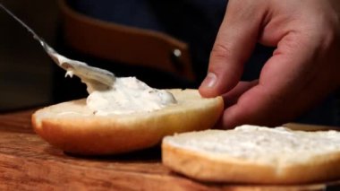 Şef Burger için çörek sos koyar. Stok görüntüleri. Şef Burger için sos hazırlar ve taze bir hamburger topuz koyar