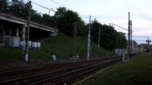 Pohled na prázdné železniční tratě v předměstích. Skladní záběry. Větvení železnice se zelenou trávou na pozadí keřů a lidí, kteří procházejí vzdáleností — Stock fotografie