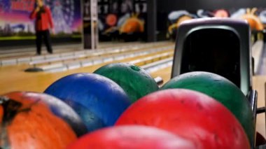 Yakın çekim Genç adam raf gelen bowling topları alıyor. Medya. Kulüp birlikte bowling oynarken rekabetçi neşeli arkadaşlar